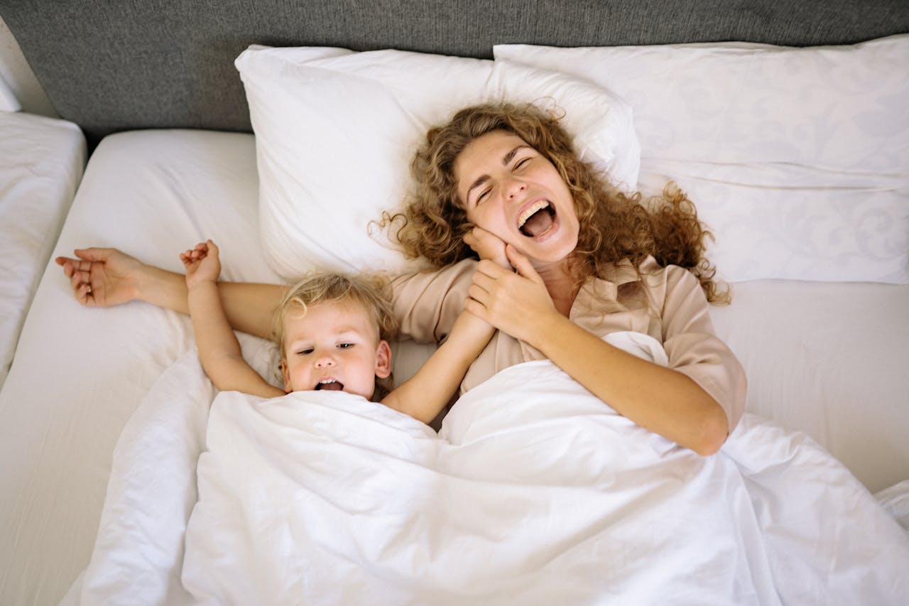 Capturing a joyful moment of a mother and her son laughing in bed at home.